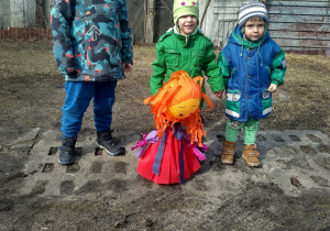 Chłopcy stoją w ogrodzie przedszkolnym z kukłą Marzanny.